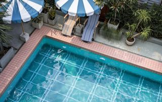 piscine extérieure avec parasols bleu et blanc et transats