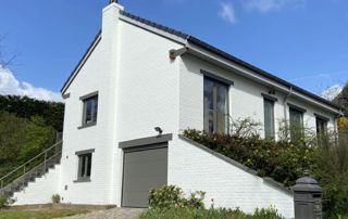 maison après travaux de peinture : murs blancs et menuiseries extérieures foncées