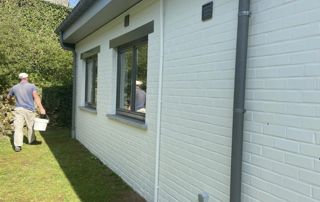 peintre en bâtiment marchant près d'une maison à repeindre