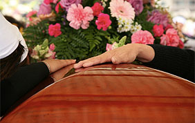 mains sur cercueil à un enterrement
