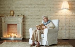 personne âgée qui lit dans un fauteuil