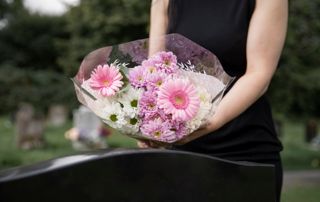 Une femme tient un bouquet de fleurs dans un cimetière