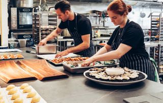 cuisiniers qui dressent des assiettes avec des migniardises